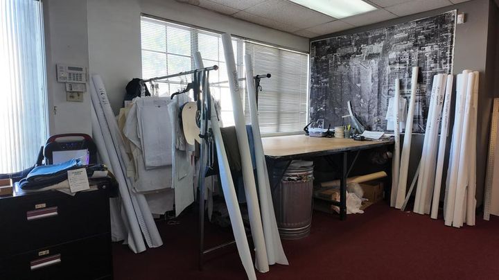 Rudy's pattern grading studio — rolled markers, hanging patterns, and cutting table